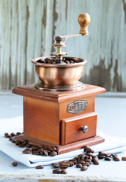 Vintage houten koffiemolen vol met geroosterde koffiebonen - Foto, afbeelding