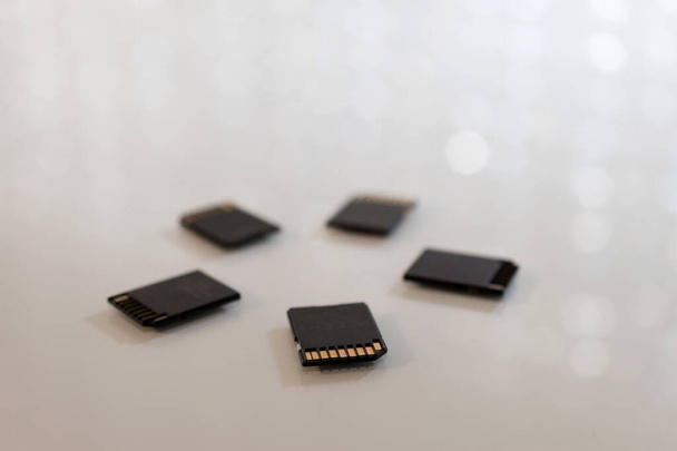 Fekete memóriakártyák körkörös alakban egy fehér asztalon. Fénykép bokeh és másolás tér. - Fotó, kép
