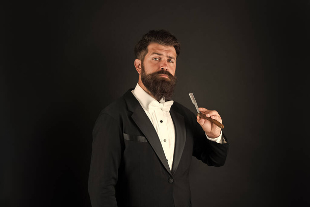 Real style for real man. Bearded man hold straight razor. Professional man with long mustache and beard hair. Brutal man in tuxedo suit. Hipster with formal look. Barbershop. November for facial hair - 写真・画像