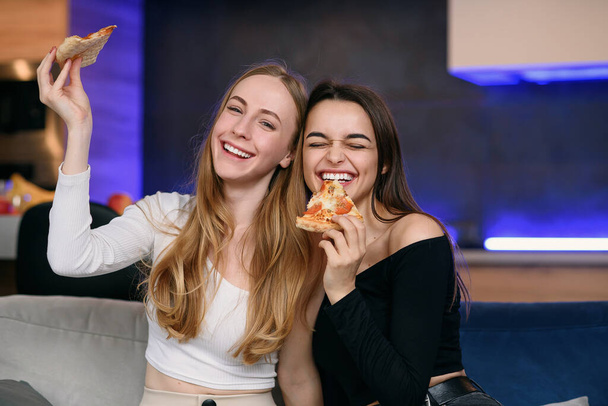 Two women having fun at home, opening pizza box, food delivery, home party - 写真・画像