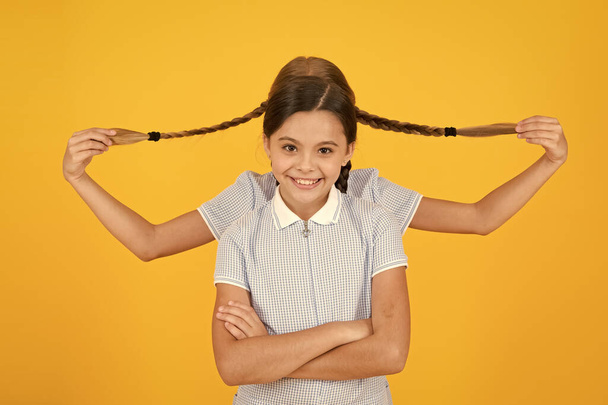playing with pigtails. hair fashion beauty. childhood happiness. small girls in school uniform. retro look. children in vintage style. old school. kid fashion. happy friends on yellow background - Фото, зображення