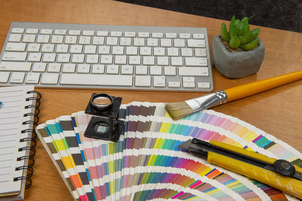 スタイラスと虫眼鏡とノートとキーボードでカラースケールし創造的なオフィス環境の要素を形成します - 写真・画像