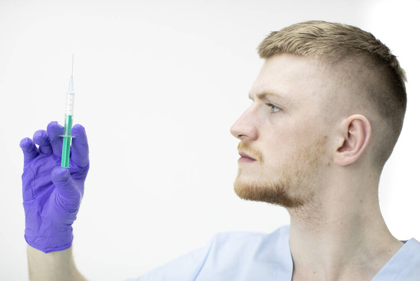 Νεαρός ελκυστικός ιατρικός βοηθός κρατά σύριγγα με εμβόλιο κατά του covid-19 - Φωτογραφία, εικόνα
