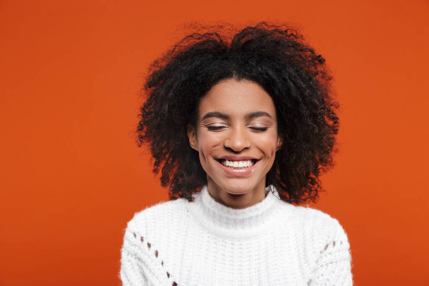 Beautiful cheerful young african woman wearing sweater standing islolated over red background, eyes closed - Φωτογραφία, εικόνα