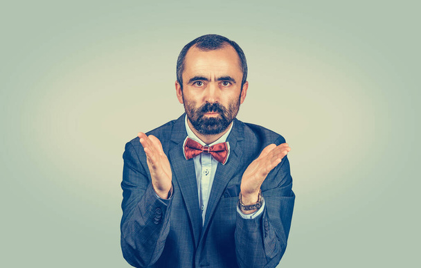 Angry young business man screaming hands in air in frustrated looking at you camera talking to you madly. Mixed race bearded model isolated on light green background with copy space. Horizontal image - Foto, Bild
