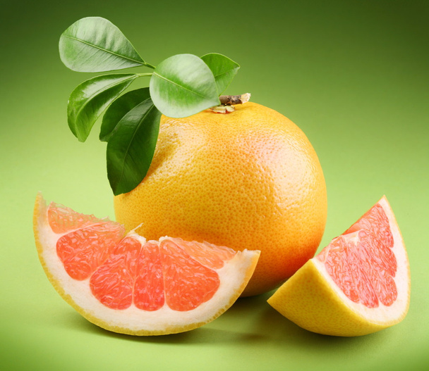 Ripe grapefruit with segment on a green background - Photo, image