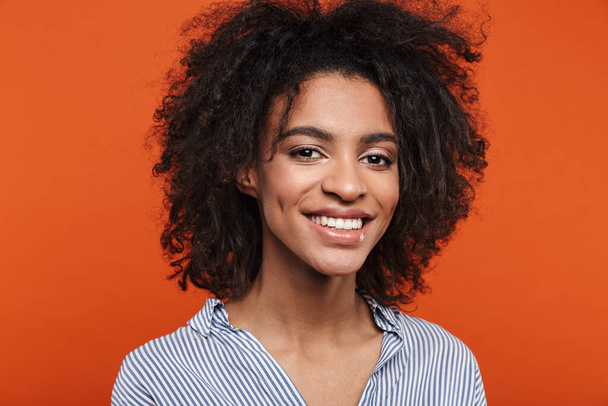 Smiling young attractive african woman wearing casual clothes standing isolated over red background, looking at camera - Valokuva, kuva