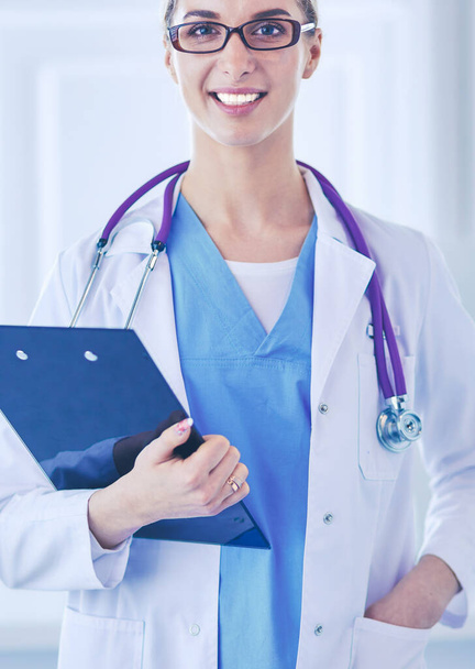 Улыбающаяся женщина-врач с папкой в форме стоя - Фото, изображение