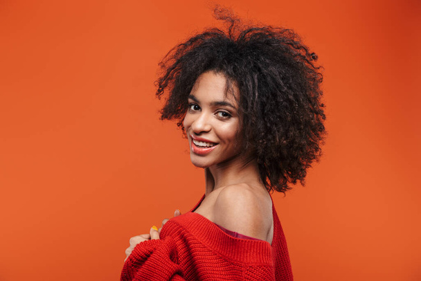 Beautiful cheerful young african woman wearing sweater standing islolated over red background - Photo, Image