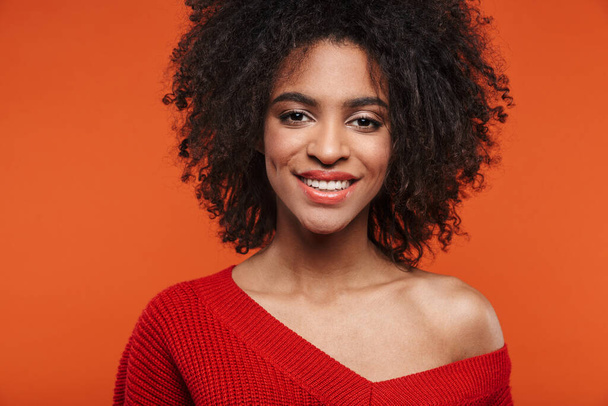 Beautiful cheerful young african woman wearing sweater standing islolated over red background, looking at camera - Photo, Image