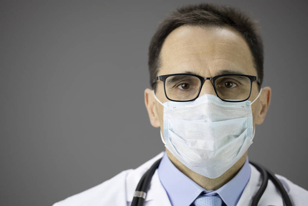 Großaufnahme Arzt in medizinischer Maske blickt in die Kamera. Coronovirus-Ausbruch, Covid-19 - Foto, Bild