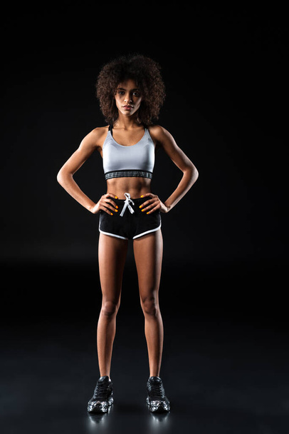 Image of young african american woman in sportswear posing with hands on waist isolated over black background - Foto, immagini