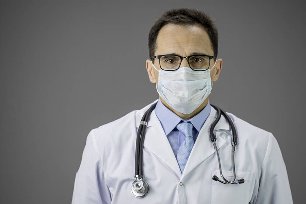 Close up male doctor in white coat, medical mask looks seriously. Copy space - Photo, Image
