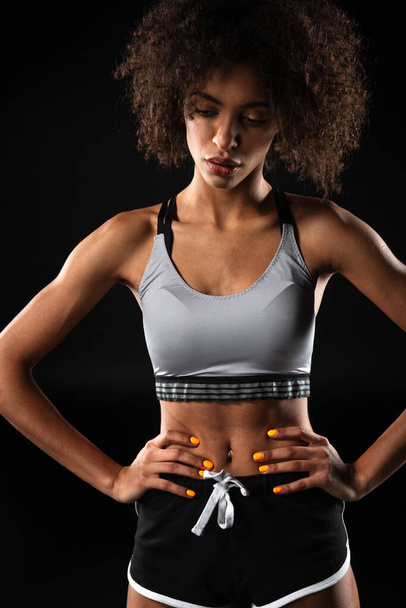Image of young african american woman in sportswear posing with hands on waist isolated over black background - Fotografie, Obrázek