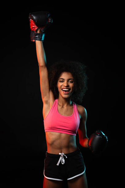Image of happy african american woman in boxing gloves making winner gesture isolated over black background - Valokuva, kuva