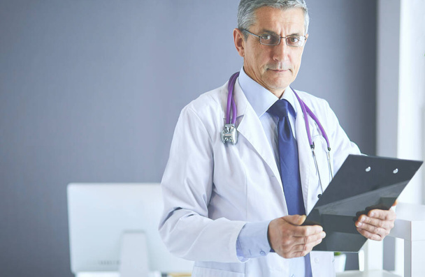 Male doctor writes notes on the clipboard in the hospital - Fotó, kép