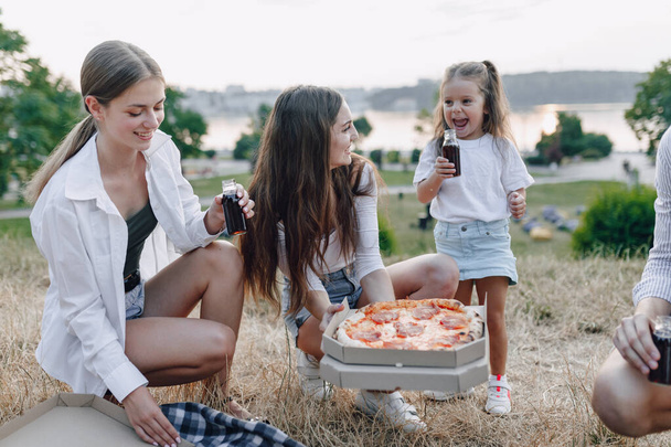 piknik ystäviä pizza ja juomat, lämmin aurinkoinen päivä, auringonlasku, yritys, hauskaa, parit ja äiti vauvan kanssa
 - Valokuva, kuva
