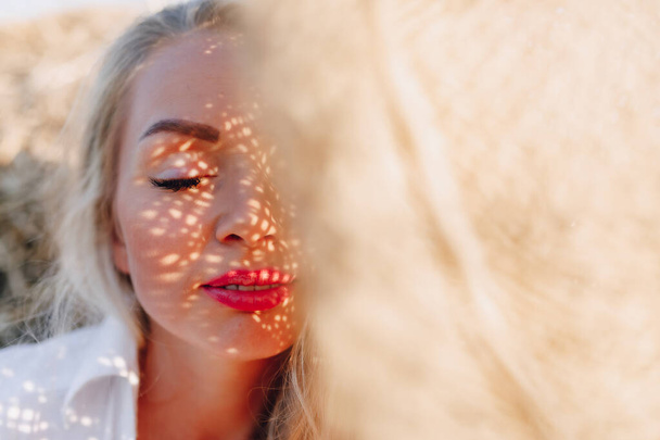 Nahaufnahme Porträt. hübsche Frau mit blonden langen Haaren auf einem Feld bei Sonnenuntergang wird von einem Sonnenhut bedeckt. Sommer, Landwirtschaft, Natur und frische Luft auf dem Land. sonnig. - Foto, Bild
