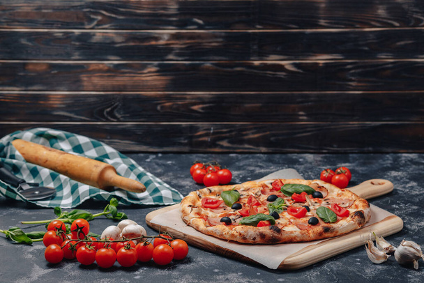 herkullinen napolilainen pizza liitutaulussa kirsikkatomaateilla, vapaata tilaa tekstille
 - Valokuva, kuva