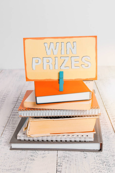 Handwriting text writing Win Prizes. Concept meaning something given for victory in a contest or competition pile stacked books notebook pin clothespin colored reminder white wooden. - Photo, Image