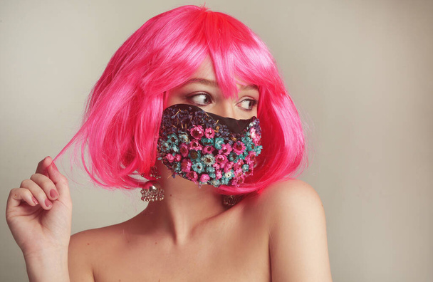 Girl with bright pink hair, anime, in a mask of flowers. Spring, joy, people should wear masks. Fashionable photo of a girl in a mask. Portrait of a bright girl in the studio. Spring, coronavirus, pandemic. - Photo, Image