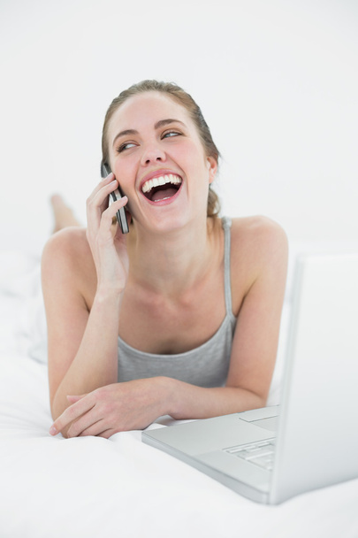 Cheerful casual woman using cellphone and laptop - Foto, imagen