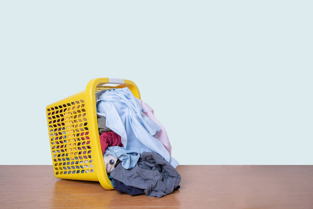 Kleidung in einem Korb mit schmutziger Wäsche auf dem Boden mit Schneideweg - Foto, Bild