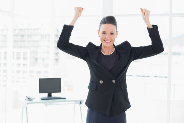 Elegant and happy businesswoman clenching fists in office - Фото, зображення