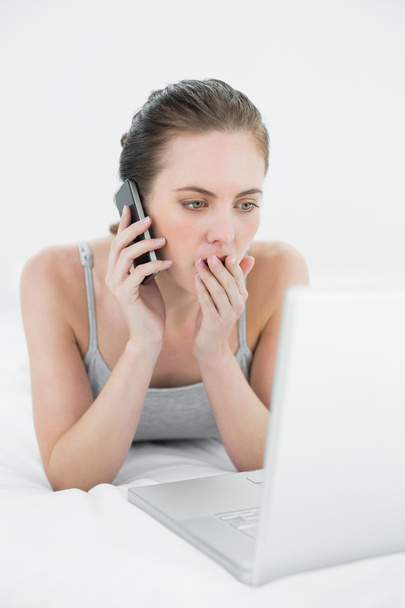 Shocked casual woman using cellphone and laptop - Photo, image