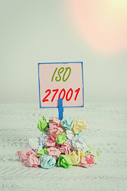 ISO 27001を示すテキスト記号。情報セキュリティ管理システムのための概念的な写真の仕様カラークランプ紙の布ピンリマインダー白い木製のスペース. - 写真・画像