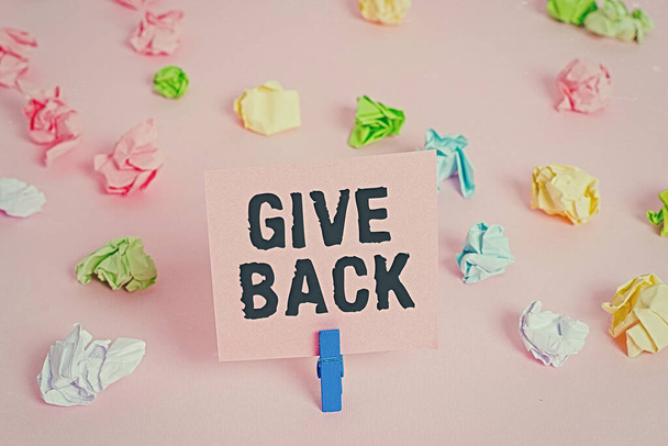 Text sign showing Give Back. Conceptual photo the act of giving someone something that they owned or had before Colored crumpled papers empty reminder pink floor background clothespin. - Valokuva, kuva