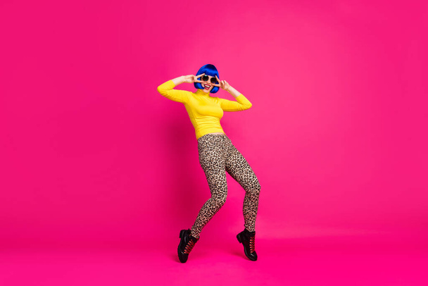 Full size photo of funny lady dance student party v-sign symbols near eyes wear specs yellow turtleneck blue wig boots leopard trousers isolated bright pink color background - Foto, afbeelding