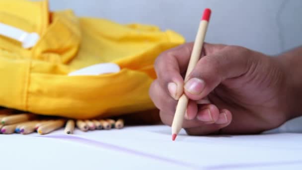 little boy draws with pencils on white paper on table - Filmagem, Vídeo