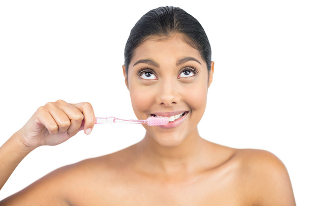 Smiling nude brunette using toothbrush looking up - Foto, imagen