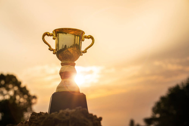 Koncepcja wygranej, Złoty puchar trofeum na szczycie góry ze wschodem słońca tle nieba. - Zdjęcie, obraz