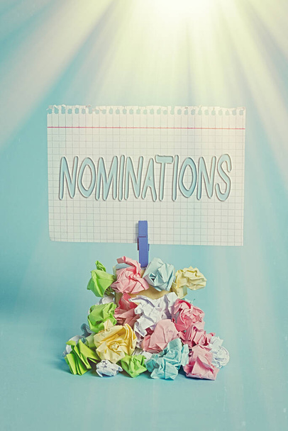 Writing note showing Nominations. Business photo showcasing the act of officially suggesting someone for a job or position Reminder pile colored crumpled paper clothespin wooden space. - Photo, Image