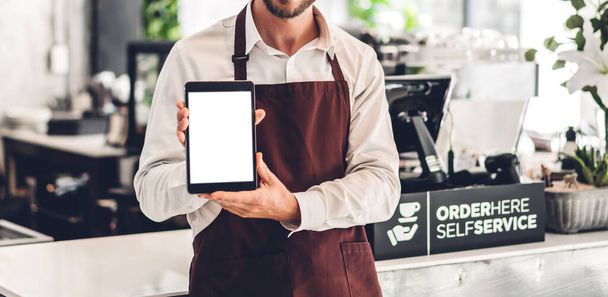 Retrato del hombre barista dueño de una pequeña empresa de pie con tableta con maqueta blanca en blanco en la cafetería o cafetería en una cafetería
 - Foto, Imagen