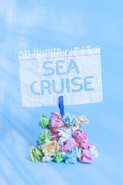 Word writing text Sea Cruise. Business concept for a voyage on a ship or boat taken for pleasure or as a vacation Reminder pile colored crumpled paper clothespin reminder blue background. - Photo, Image