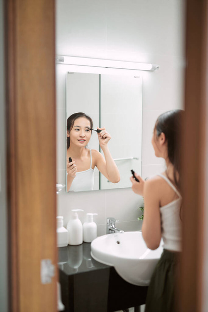jonge vrouw zetten mascara op haar wimpers - Foto, afbeelding