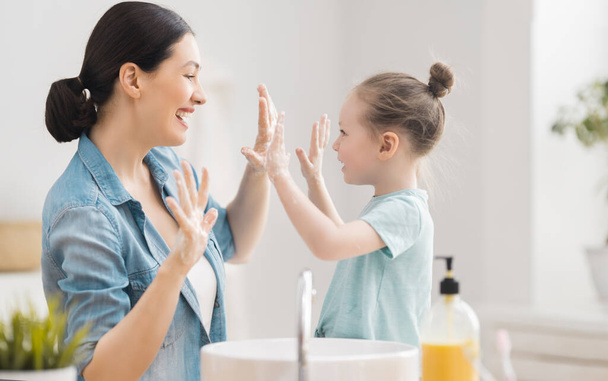 A cute little girl and her mother are washing their hands. Protection against infections and viruses.    - 写真・画像