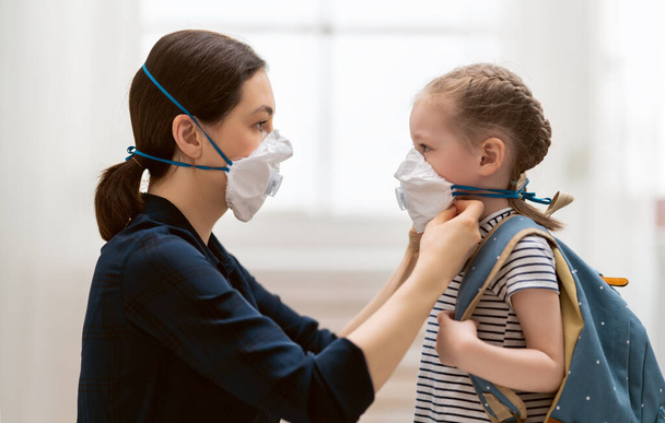 Mother and child wearing facemasks during coronavirus and flu outbreak. Virus and illness protection, home education and quarantine. COVID-2019 - Foto, Imagem