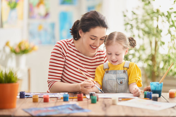 Happy family. Mother and daughter painting together. Adult woman helping to child girl.  - Photo, Image