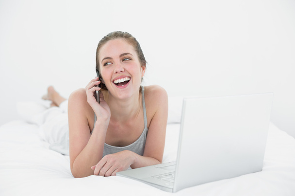 Cheerful casual woman using cellphone and laptop - Foto, Imagem