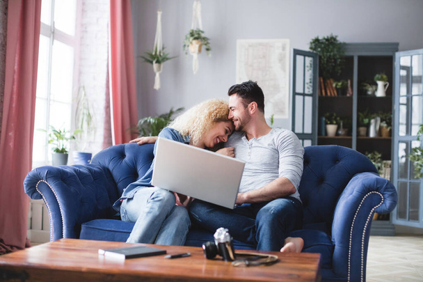 Joyful couple with a laptop at home. Choose online. - 写真・画像