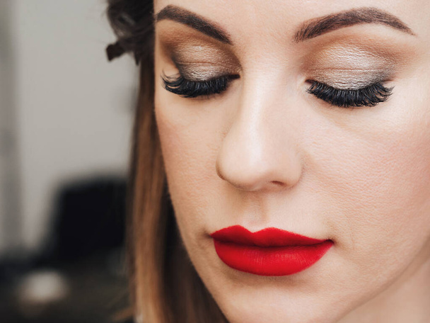 face of a woman with professional makeup with long eyelashes and red lipstick - Foto, Imagem