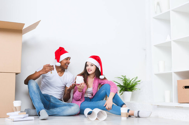 Happy young couple in Santa hats in new house. Moving in new home - Foto, Imagen