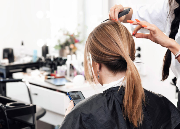 cabeleireiro faz um penteado cauda para uma mulher com cabelo marrom longo
 - Foto, Imagem
