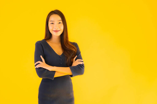 Portret pięknej młodej azjatyckiej kobiety z akcją na odizolowanym żółtym tle - Zdjęcie, obraz