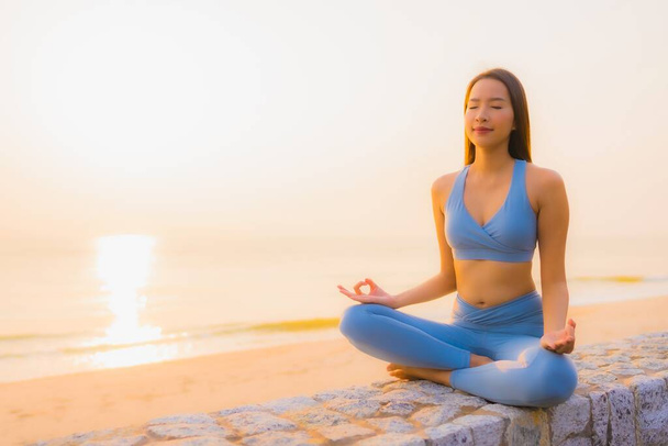 Porträt junge asiatische Frau meditieren rund um Meer Strand Ozean bei Sonnenaufgang für die Gesundheit - Foto, Bild