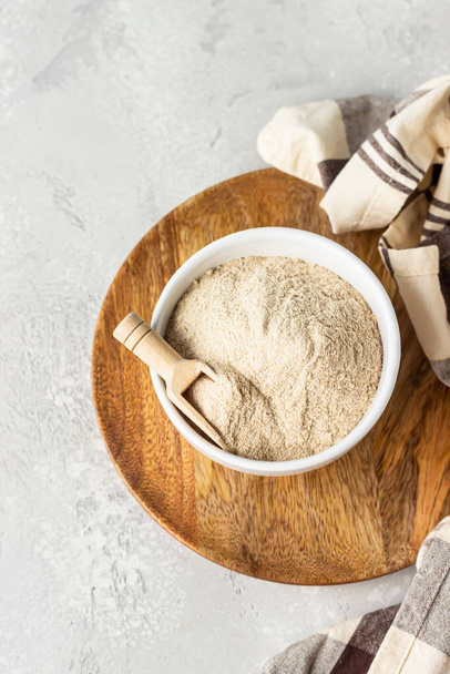 Buckwheat flour and a small wooden scoop with flour in a bowl, light grey concrete background. Gluten free flour, healthy nutrition. - Φωτογραφία, εικόνα